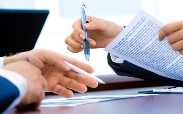 profissional lendo e assinando contrato de prestacao de servicos com seguranca juridica